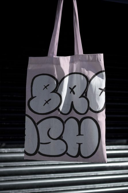 White tote with bold outlined bubble letters in black ink on reflective surface